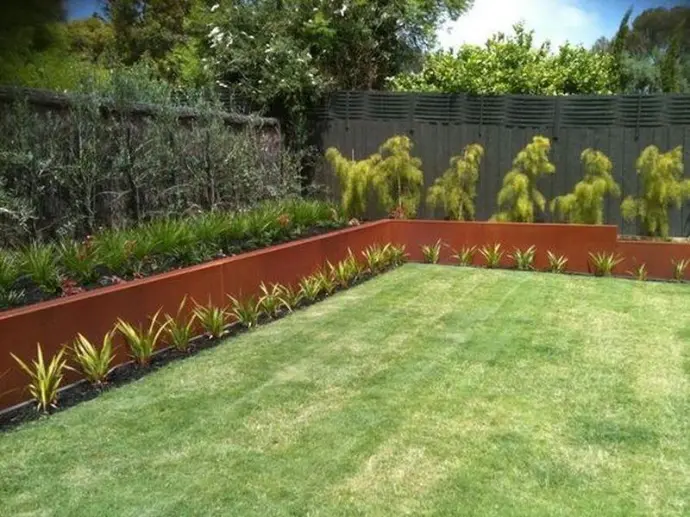 Close-up of Corten steel protective patina vs deteriorating sleeper retaining walls.